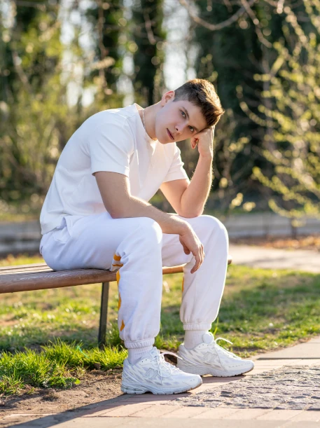 Filip Konewecki siedzący na ławce w parku